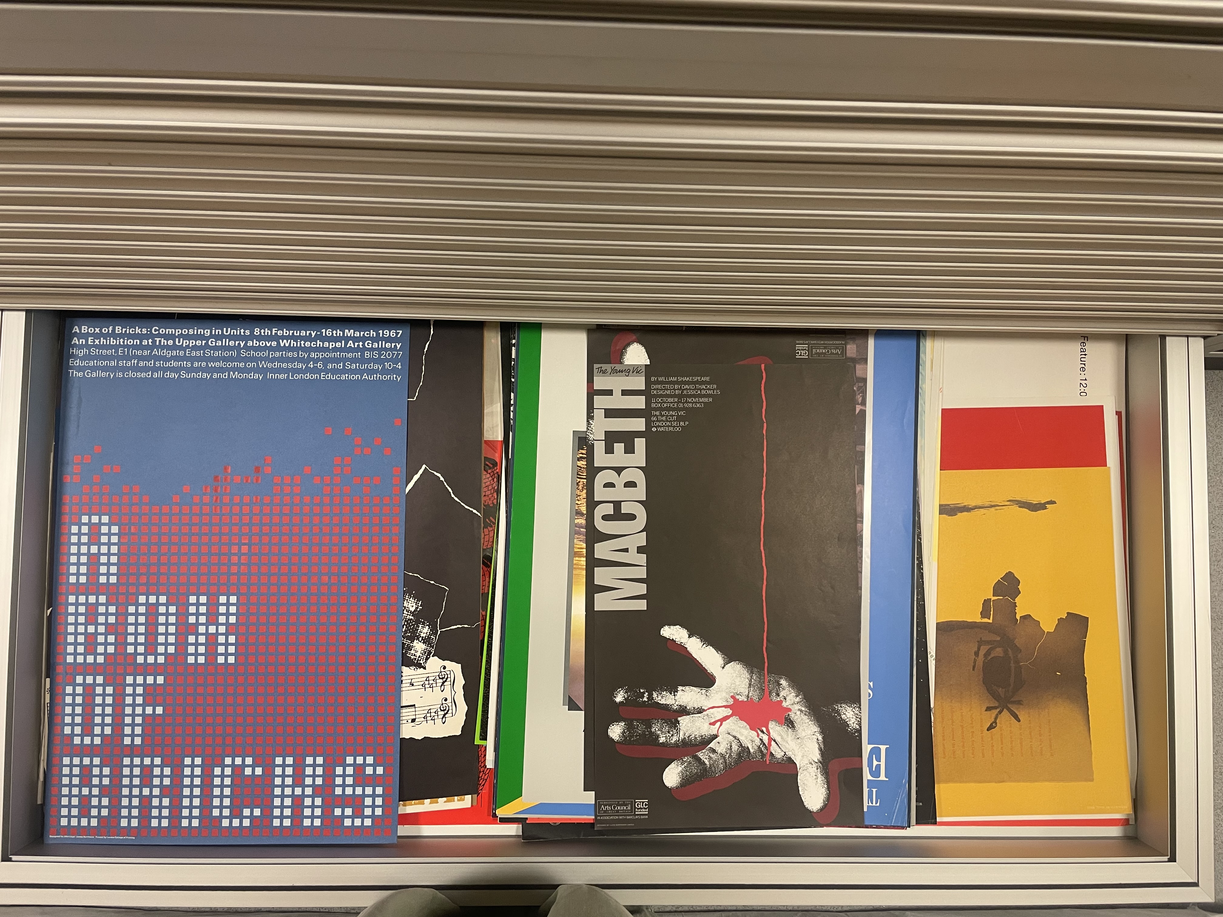 A view upon posters of various colours in a metal plan chest drawer.