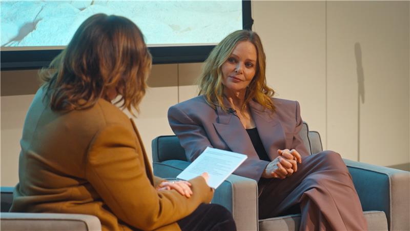 An image of two women sitting and chatting on what appears to be a stage