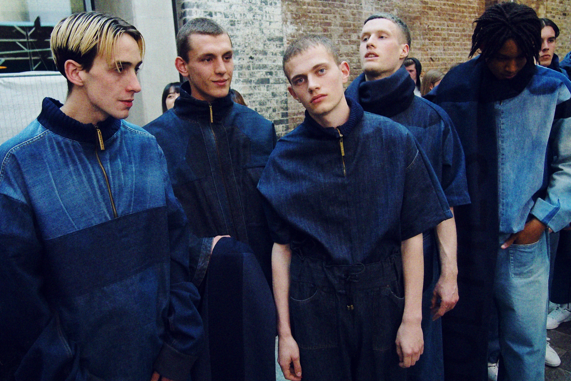 Five men wearing denim zip through blue garments