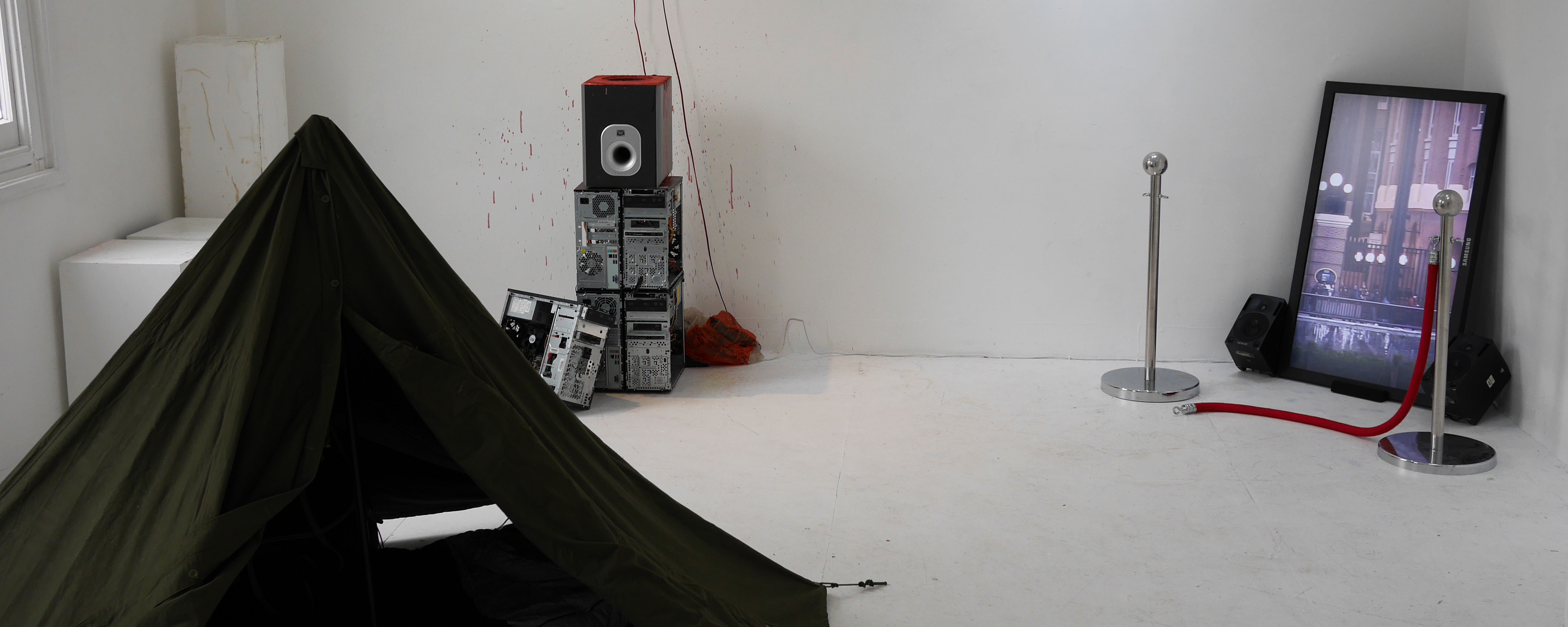 Installation showing a black tent, a screen and speakers.