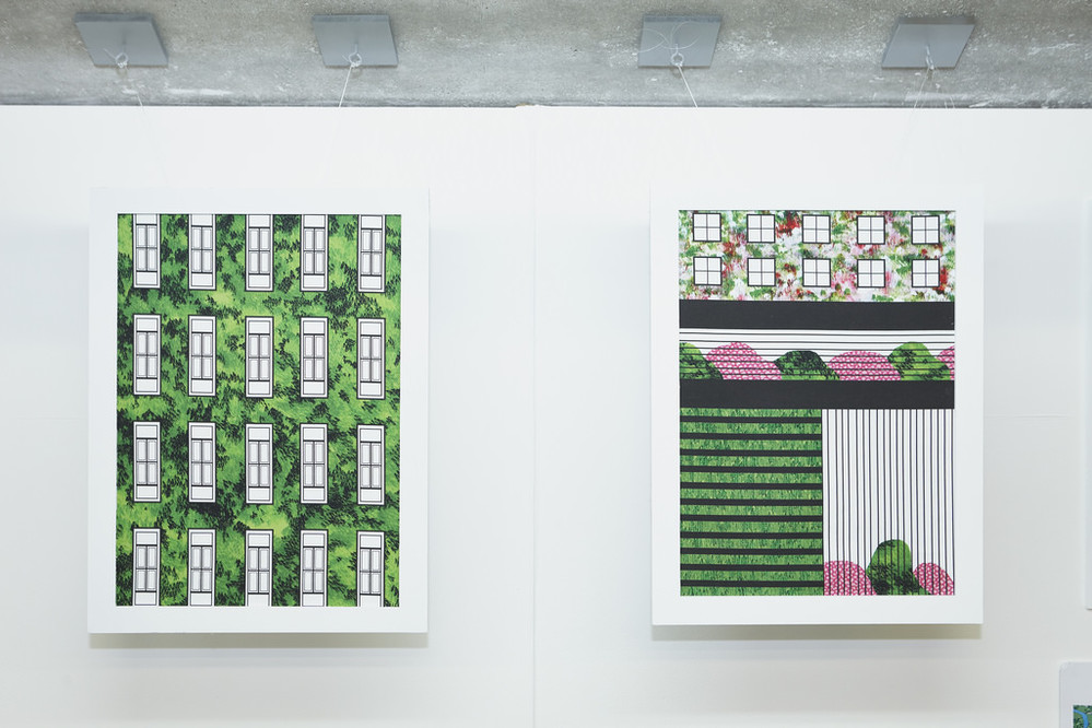 2 paintings in white frames on a white wall showing buildings and symmetrical designs integrated with the green of nature