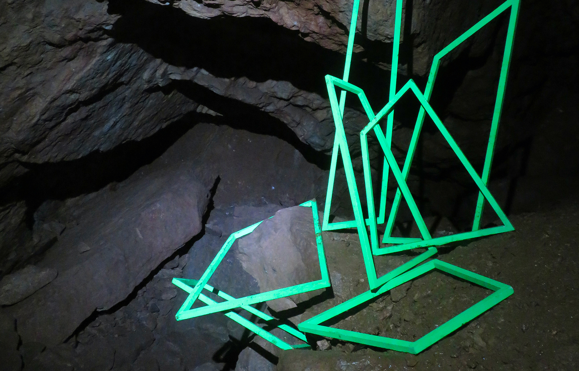 Green linear sculpture in a cave
