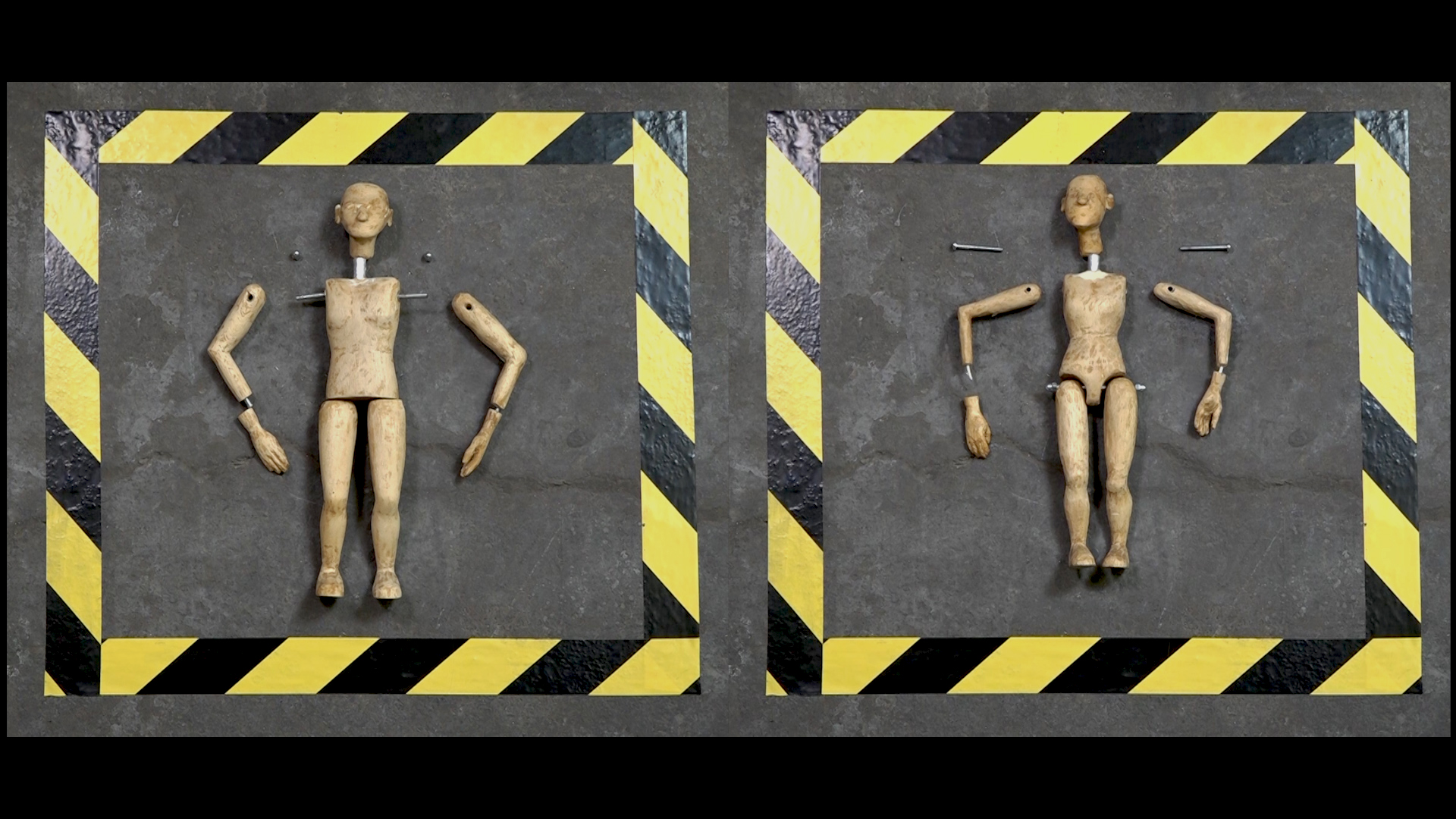 Two wooden puppets with limbs taken apart, surrounded by black and yellow tape