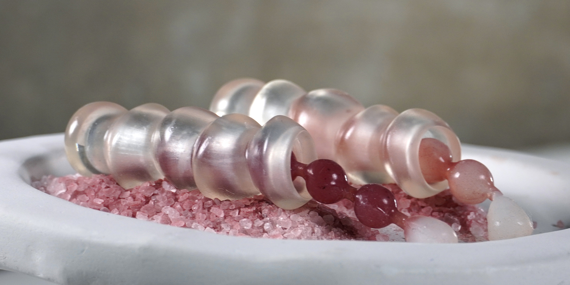 Sheathed pink beads on a bed of pink grain
