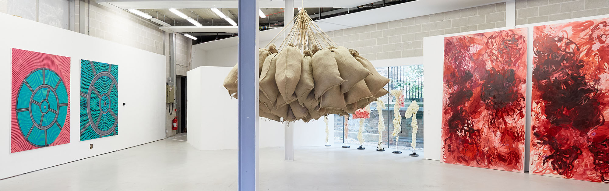 Two sets of paintings and a sculpture of hanging sacks from the ceiling as part of the MA Fine Art Summer Show