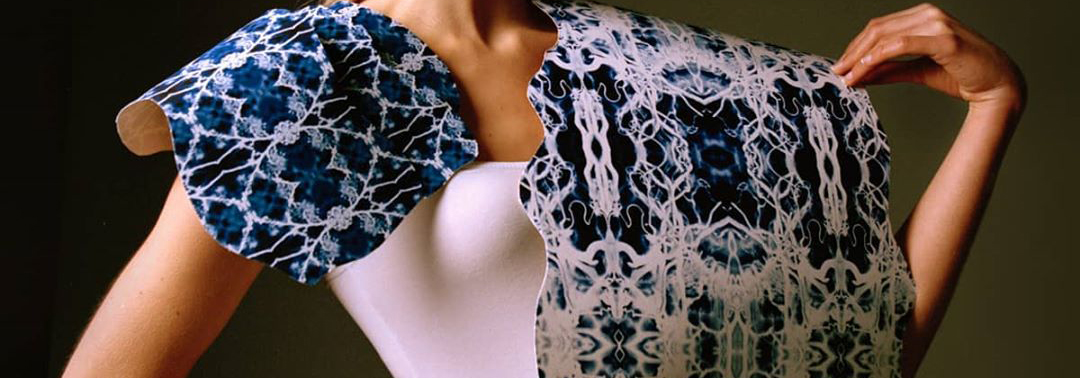 Female model wearing white top and white and blue printed cape