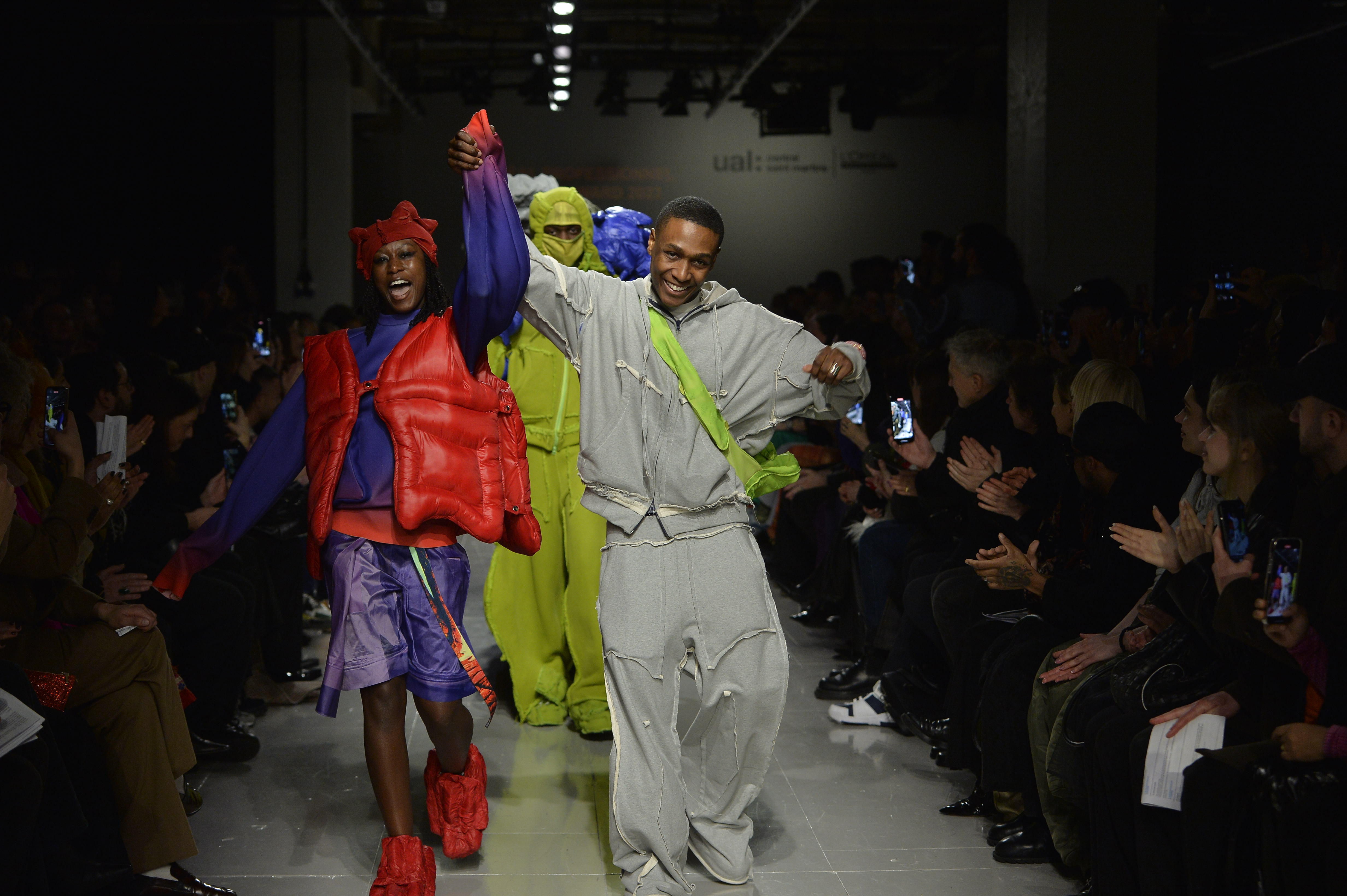 Yaku Stapleton on the runway celebrating with his models beside and behind him. 