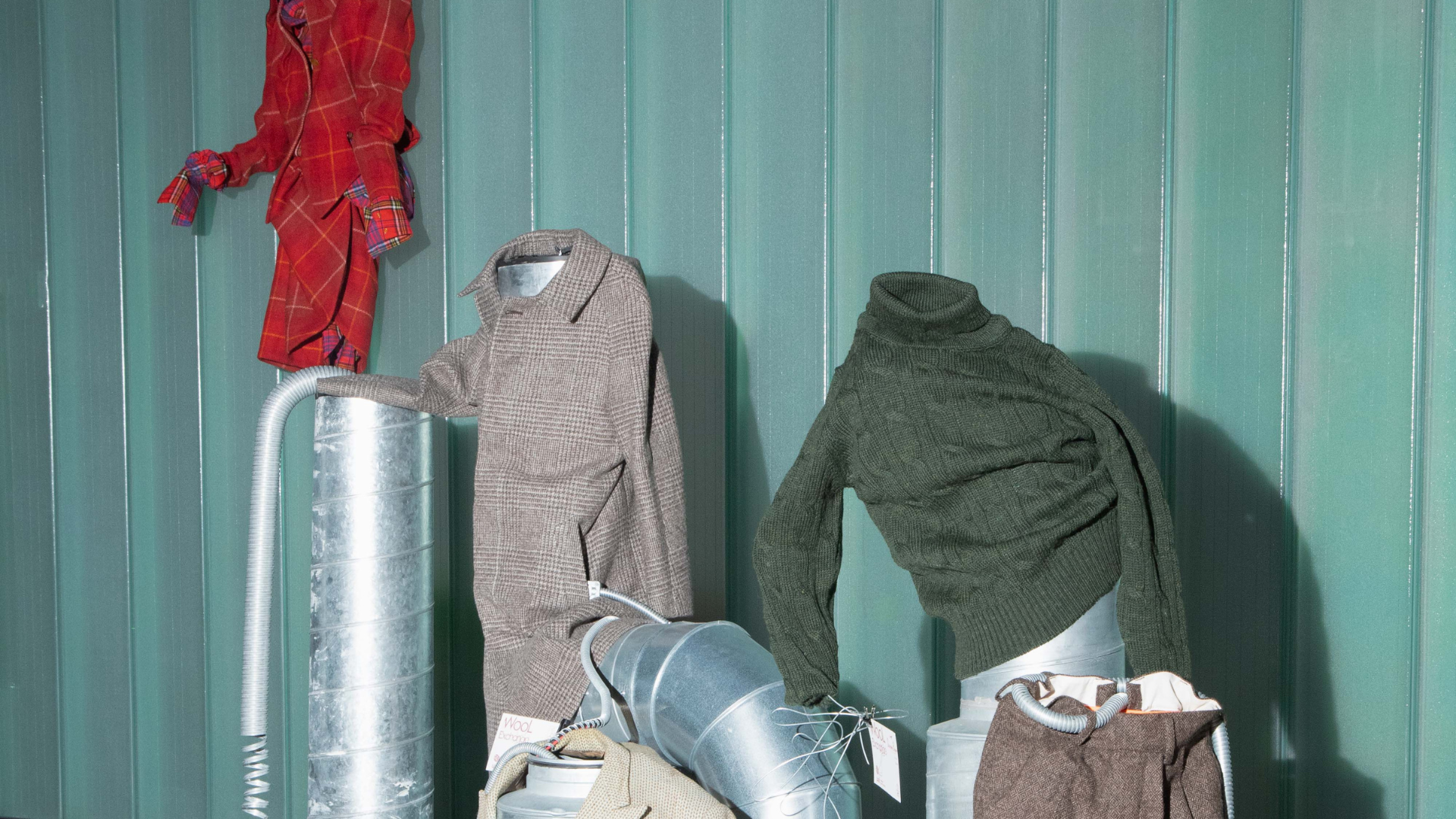 A wool installation with garments placed over industrial fixtures