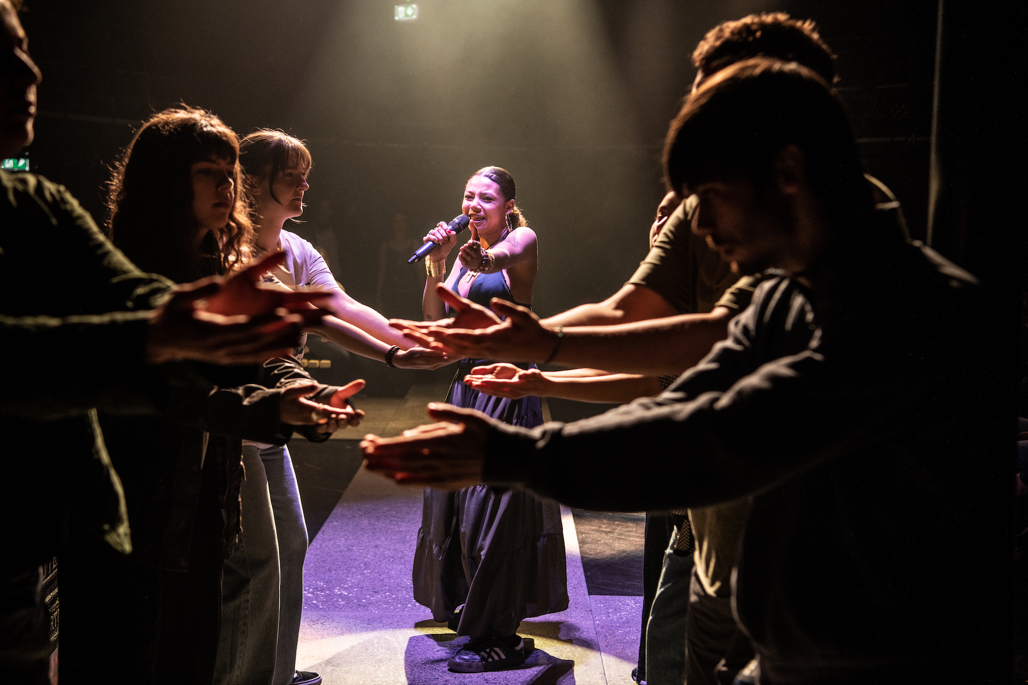 A group of performers holding their arms towards each other