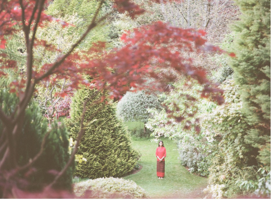Figure dressed in red standing  in garden