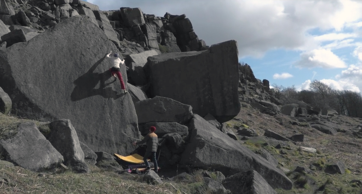 Woman climbs rock-face in mountain.