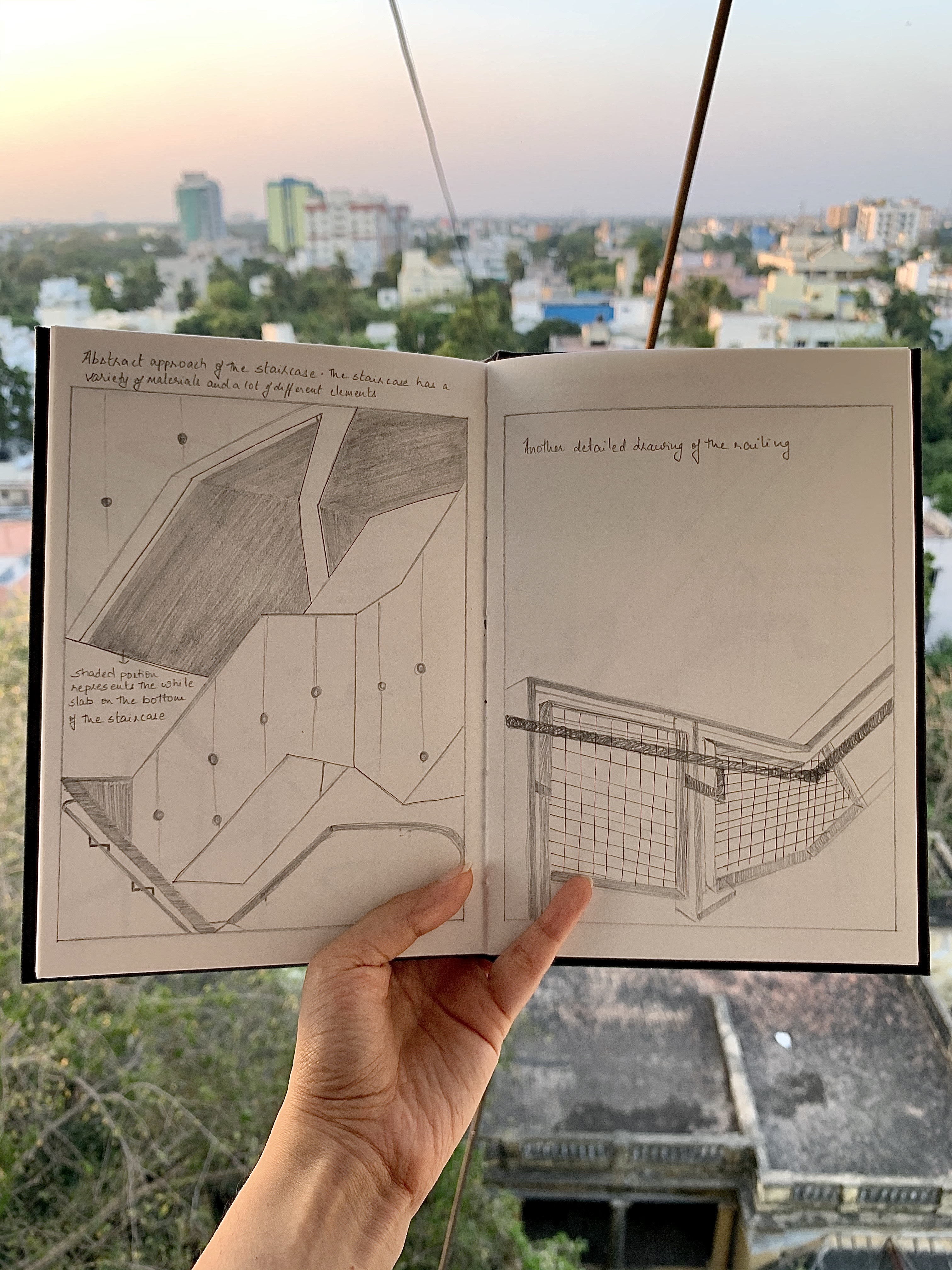 Pencil illustrations in a notebook held over a city skyline