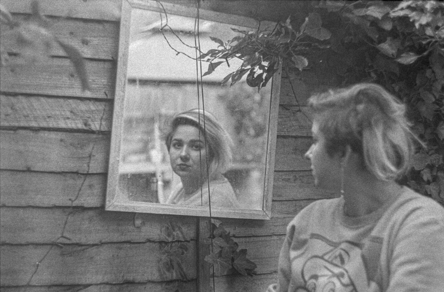 A woman looks at a mirror over her shoulder.