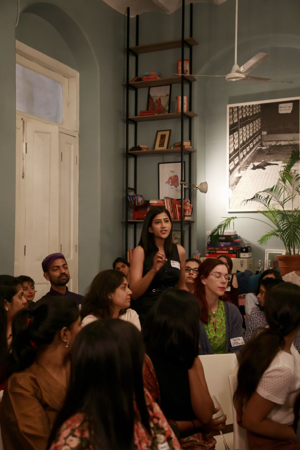 A woman stood up holding a microphone. People are seated around her