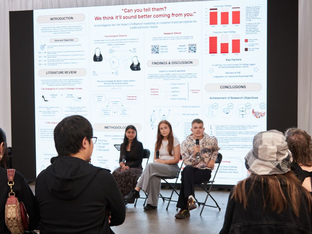 Panel of four speaking to a crowd with screen behind them