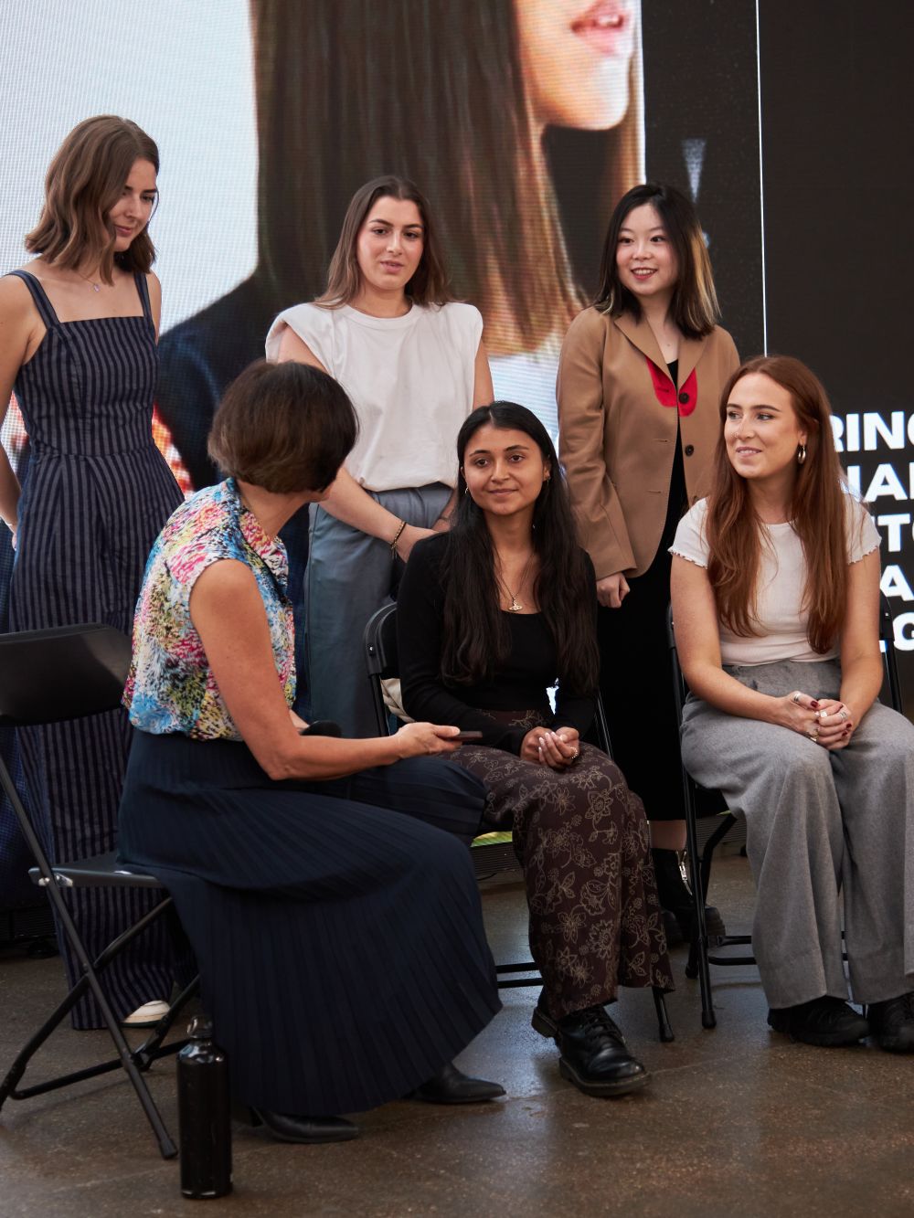 Group of people sitting in front of a screen, chatting