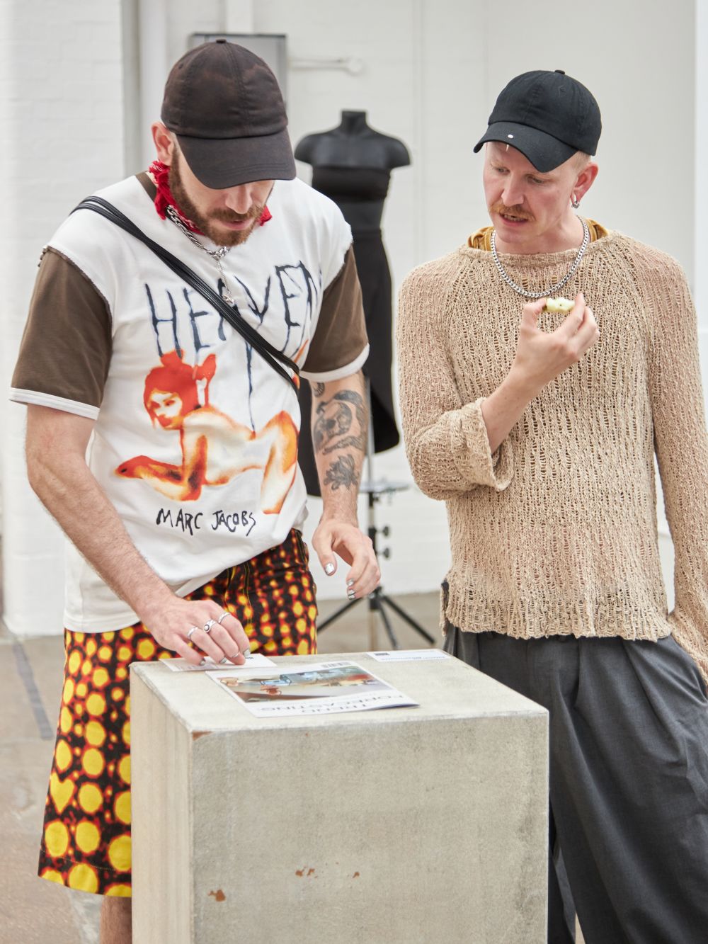 Two people read a magazine on a plynth