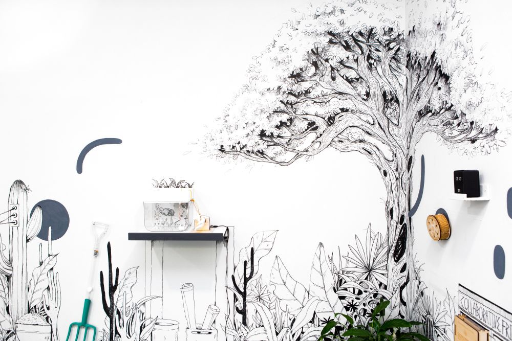 Wall installation showing a tree and garden equipment drawn onto the wall in black marker pen.