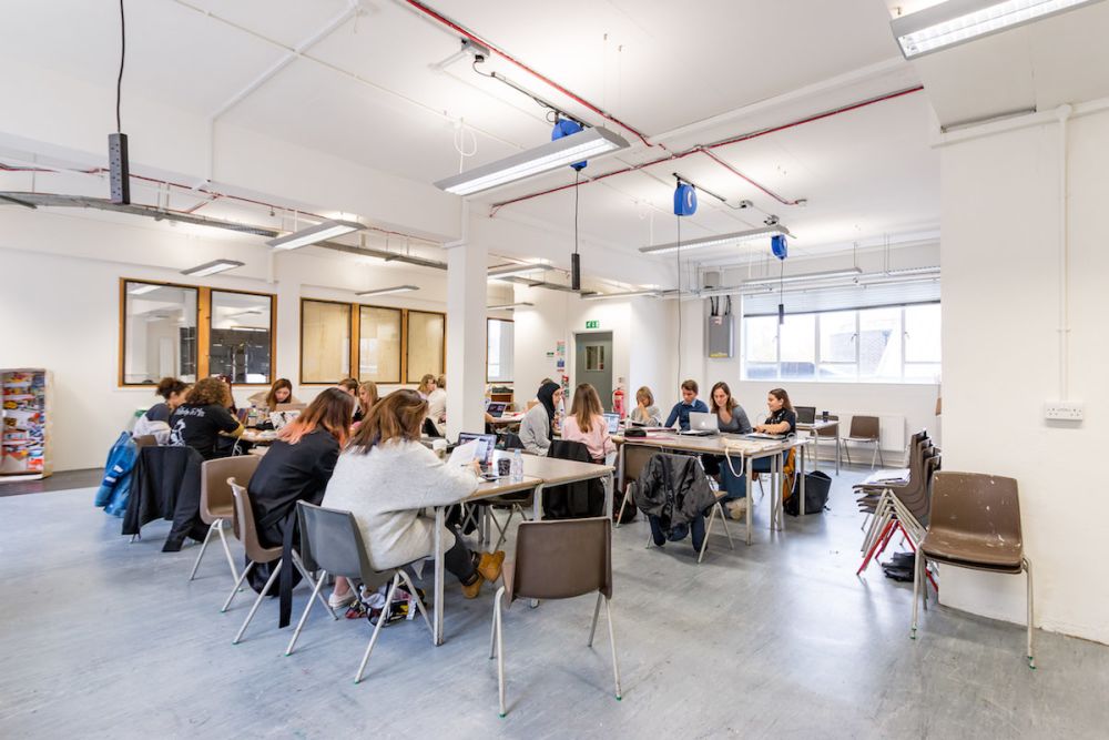 Students working at a desk inside Central Saint Martins' Archway campus