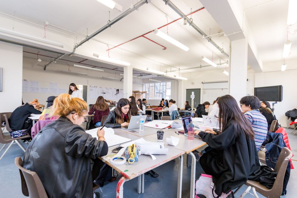 Students working at a desk inside Central Saint Martins' Archway campus