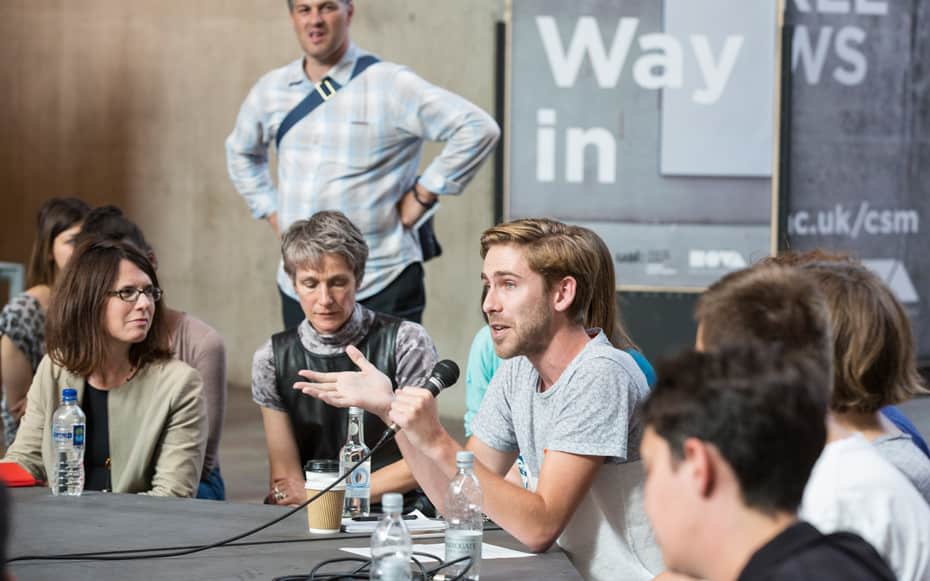A man sat at a table speaking into a microphone 