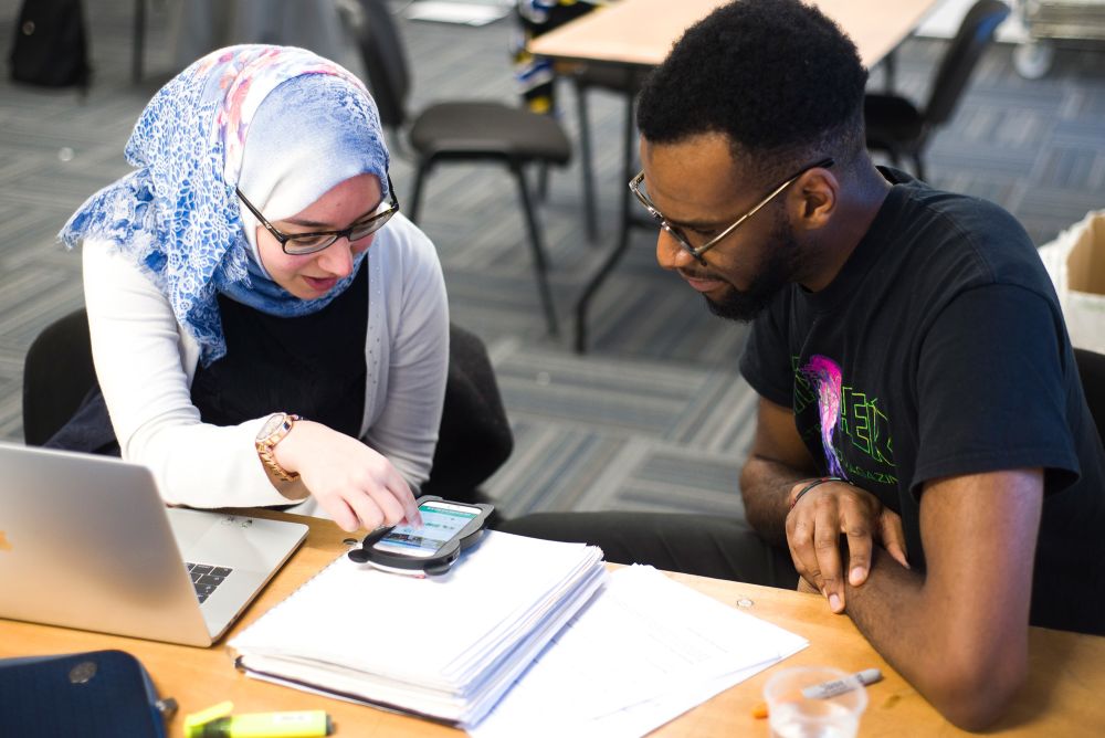 Students looking at app on phone screen.