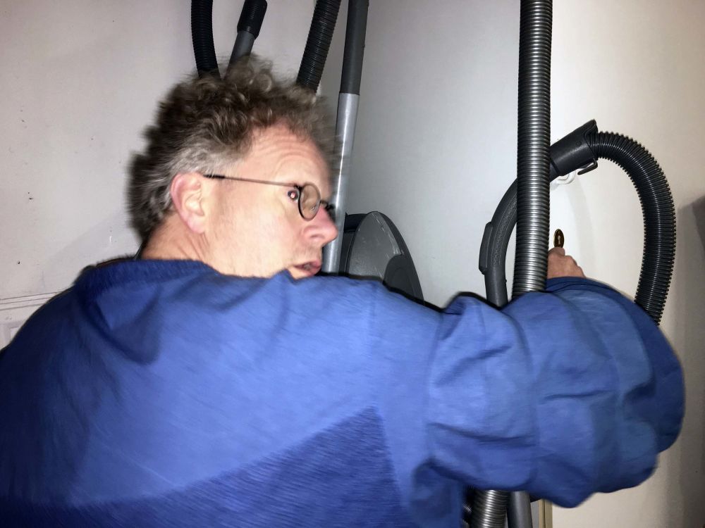 Man wearing blue top reaching for hoover