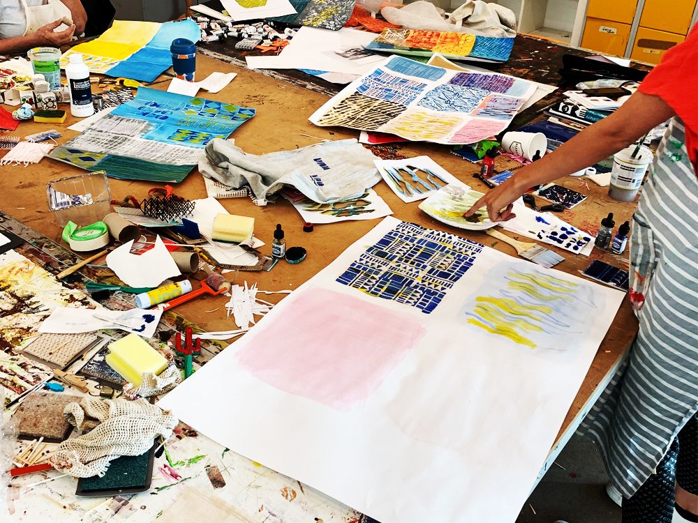 Students working in textile design studio, work and materials on table.