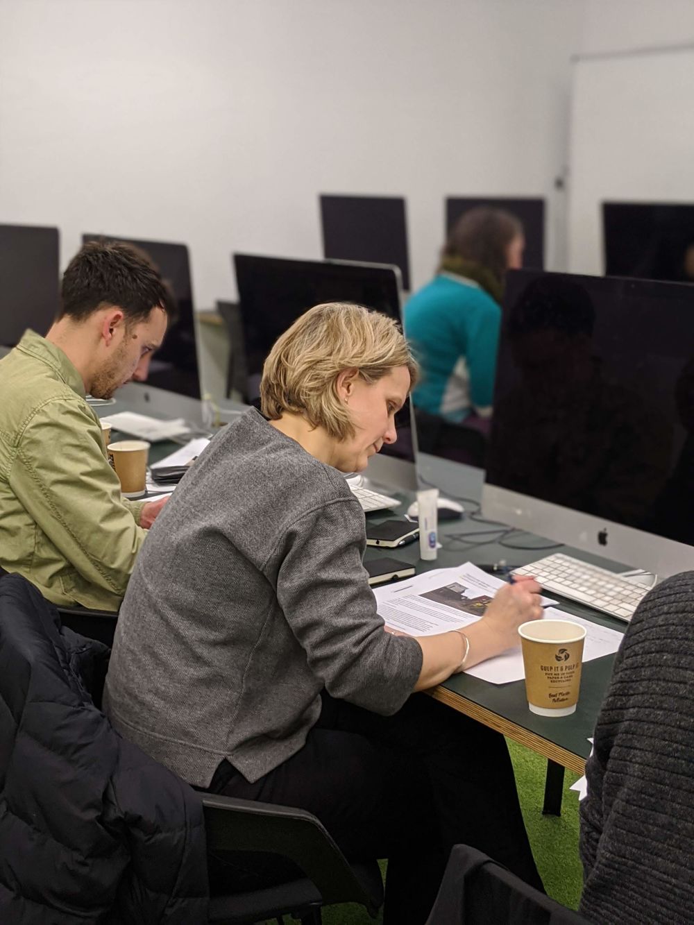 two people working on paper in front of computers