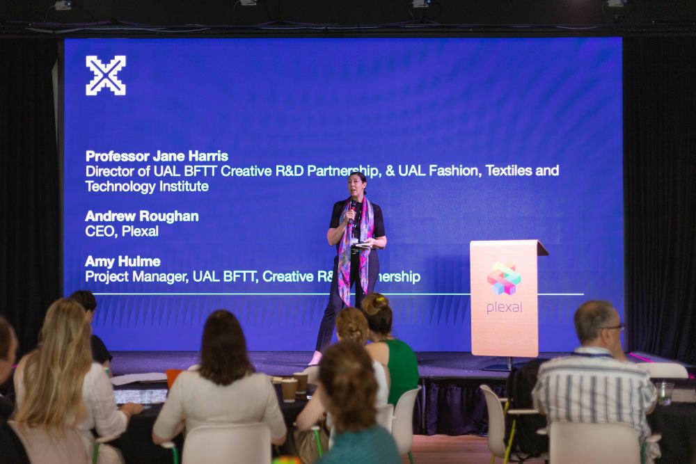 a person standing on a stage in front of an audience and giving a speech