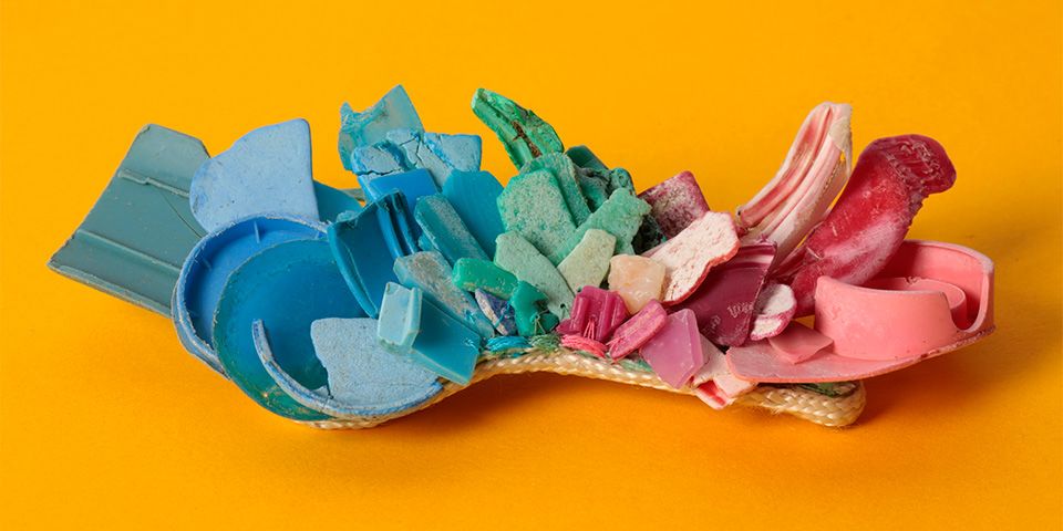 Bright pieces of discarded plastic laid out on a bright orange background