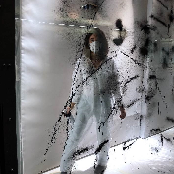 women in a a lit up window space painting glass black