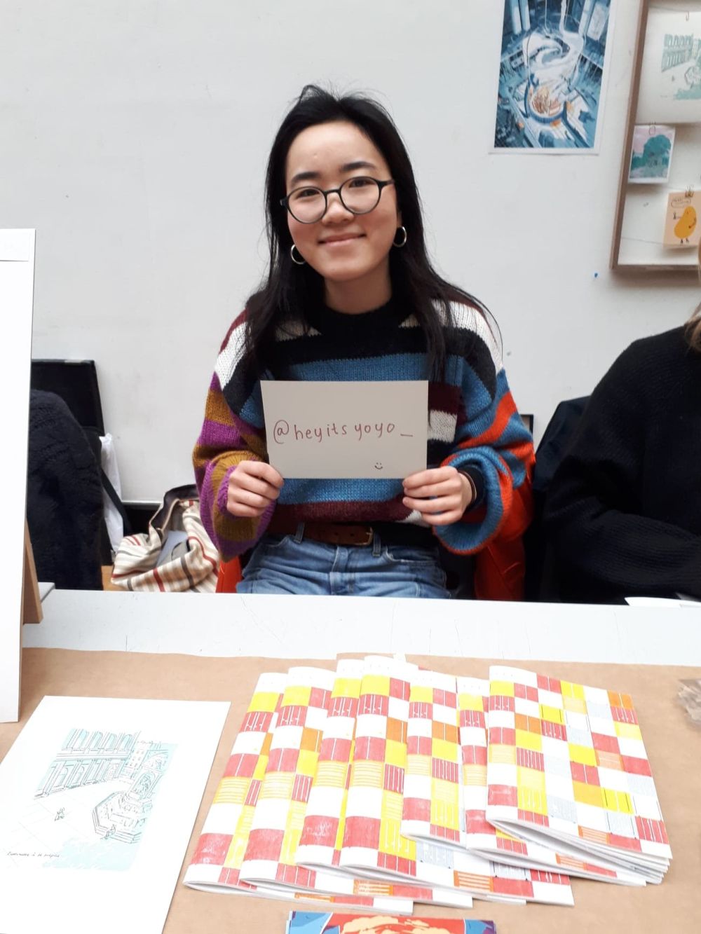 student at holiday market holdin gup a card with instagram handle written onto it