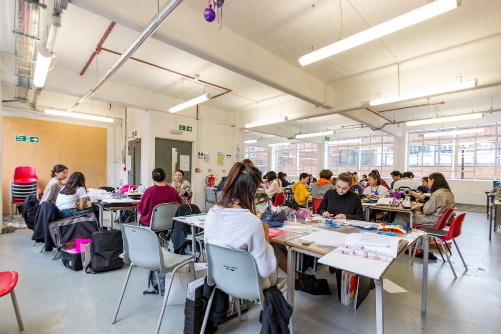 Students working at a desk inside Central Saint Martins' Archway campus