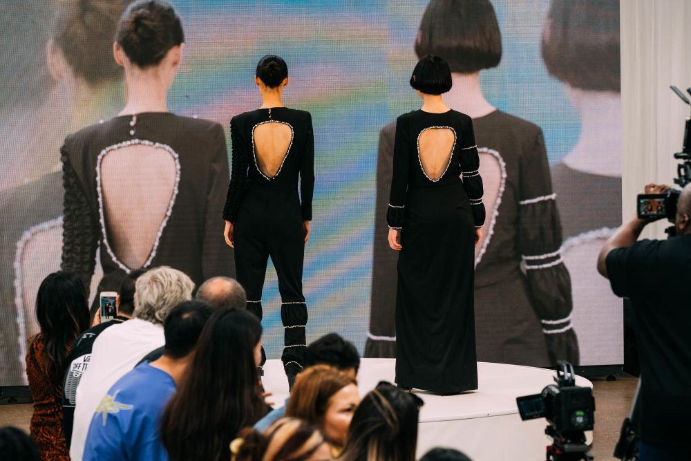 Two models on stage, wearing bold inflated outfits