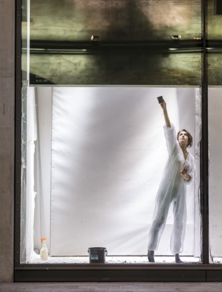 women in a a lit up window space painting glass black