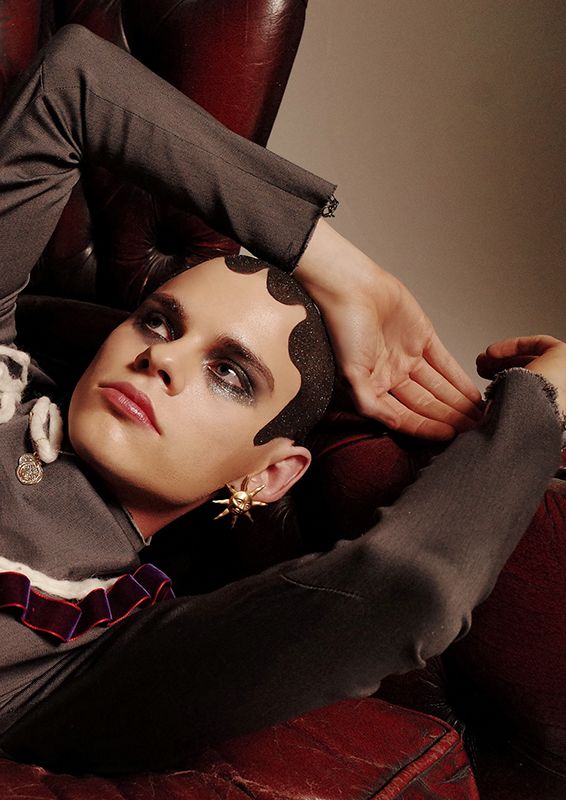 Model resting arm on head with short hair and heavy eye makeup