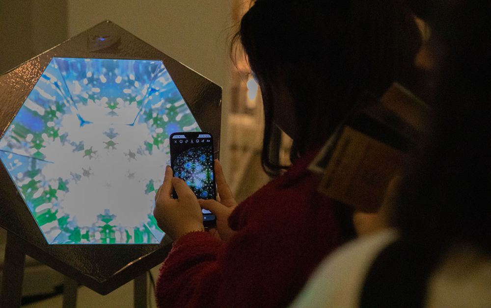 A visitor takes photographs of a hexagonal student work