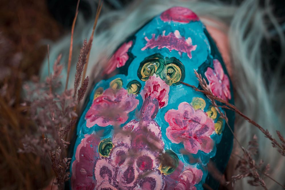 A man lies on grass while wearing a colourful full-face mask.