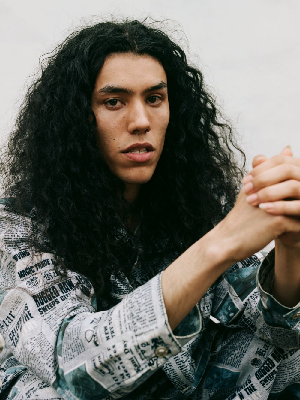 Close up photograph of a young man with long curly hair