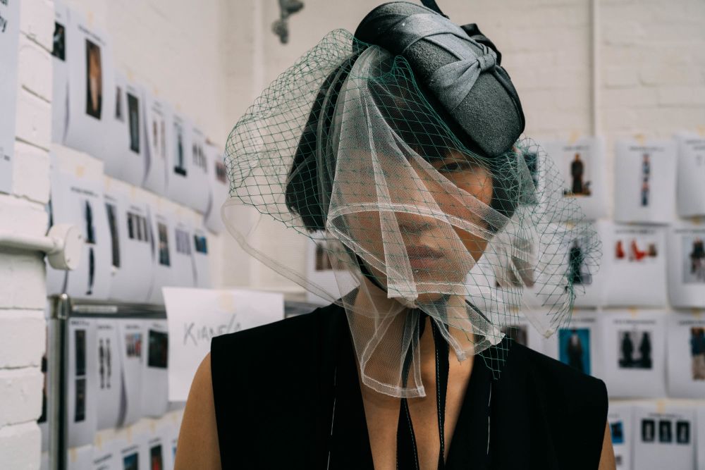 A model stares into the camera with their face partially covered