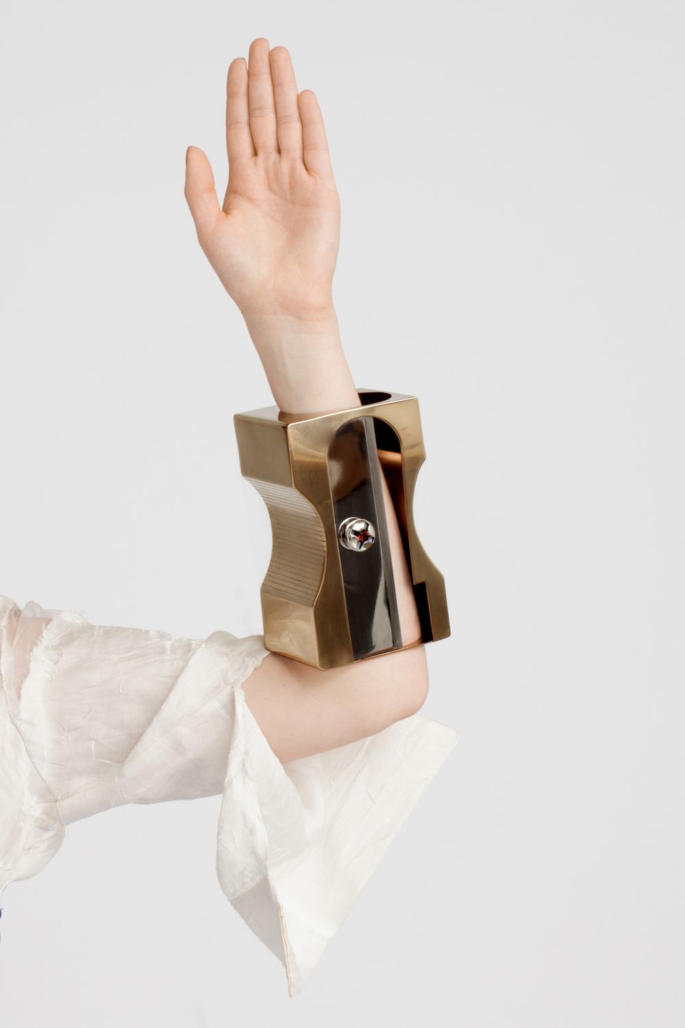A model wearing a bracelet that resembles a large gold pencil sharpener