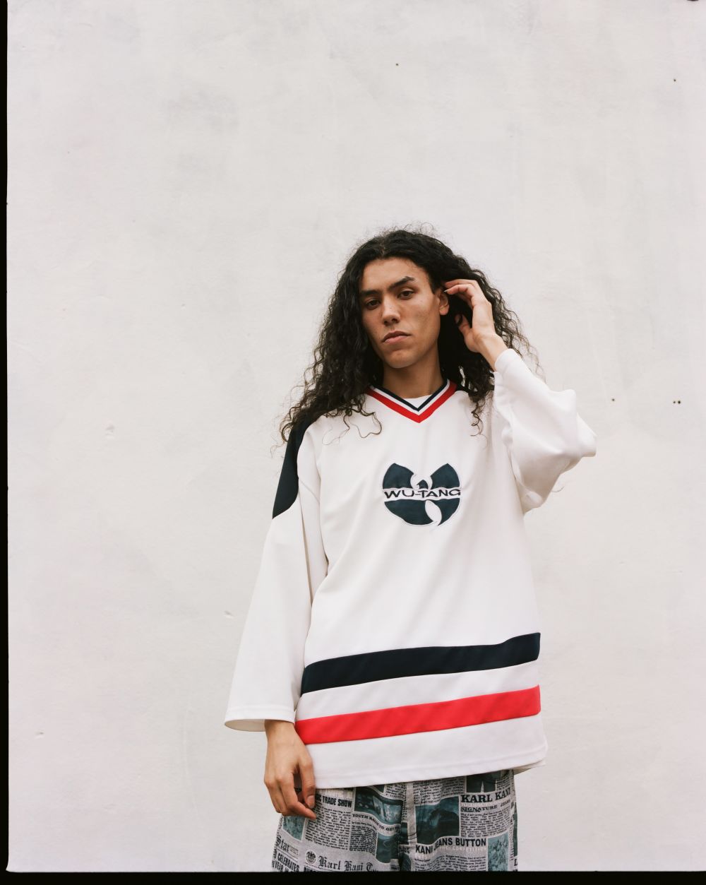 Photograph of a young man wearing a sweatshirt with a Wu-Tang logo