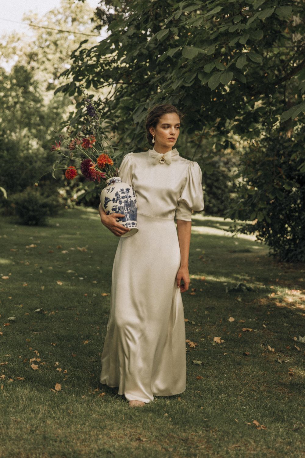Model wearing wedding dress holding a vase with flowers