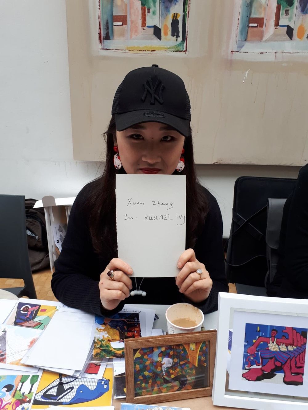 student at holiday market holdin gup a card with instagram handle written onto it