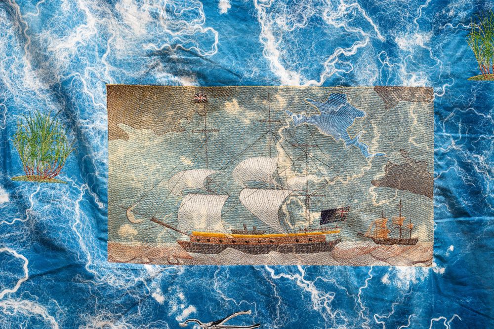 An embroidered sailboat on a larger piece of blue and white textile