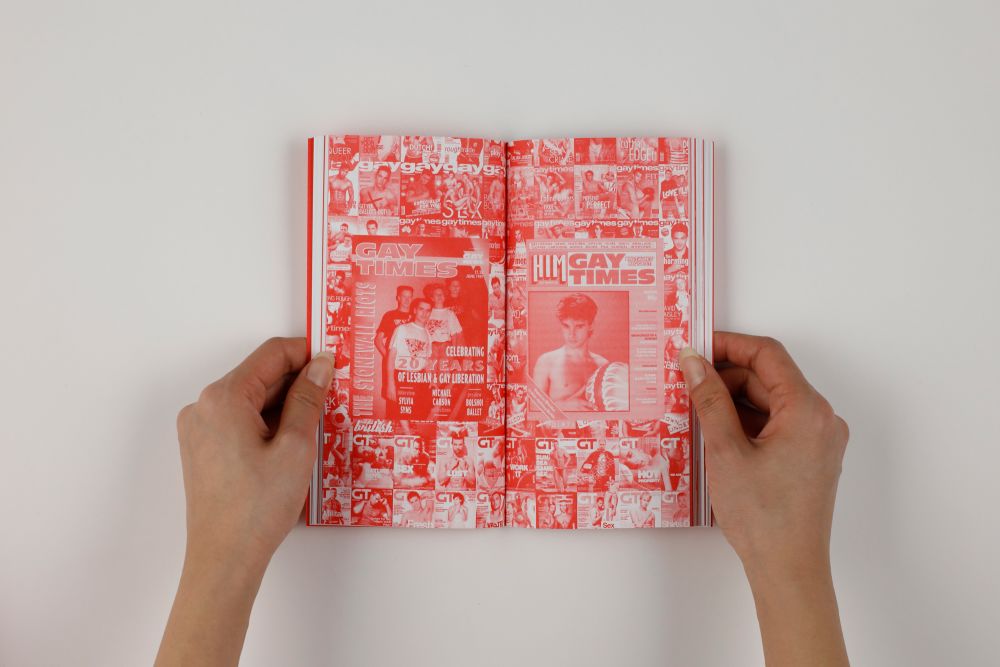 Open spread of publication A Line Which Forms A Volume showing red pages with magazine cuttings of Gay Times.