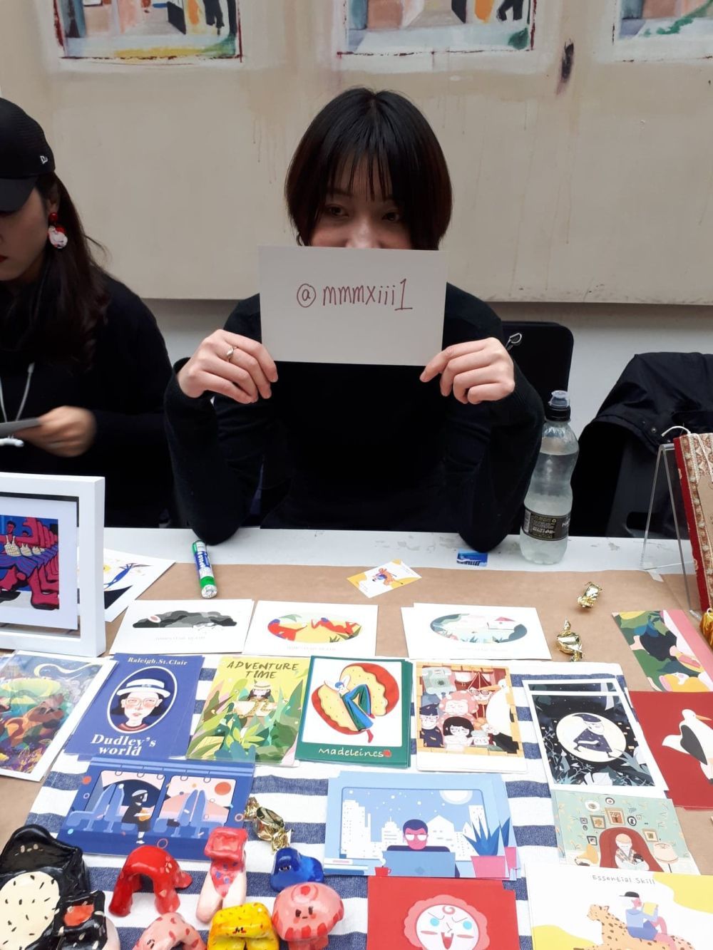 student at holiday market holdin gup a card with instagram handle written onto it