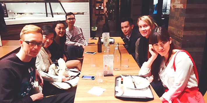 7 people sat around a table looking at the camera