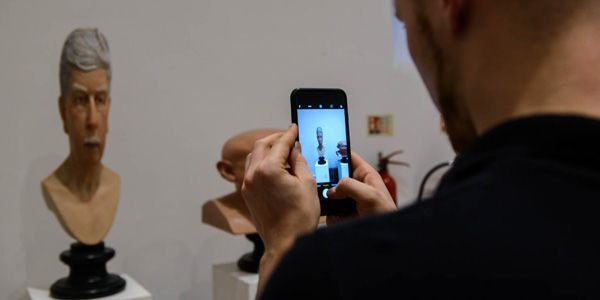An attendee takes a photograph of a John Humphreys sculpture